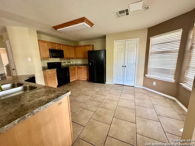 kitchen with black appliances, sink, and light tile patterned floors