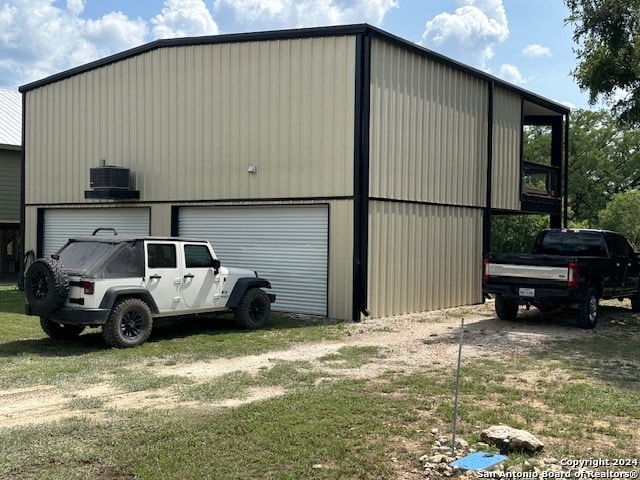 view of outdoor structure with central air condition unit, a garage, and a yard