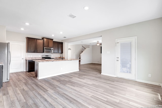 kitchen with light hardwood / wood-style flooring, dark brown cabinets, ceiling fan, appliances with stainless steel finishes, and a center island with sink