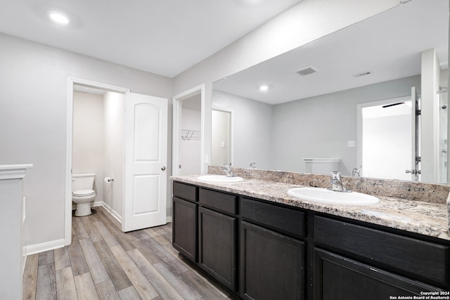 bathroom featuring dual vanity, toilet, and wood-type flooring