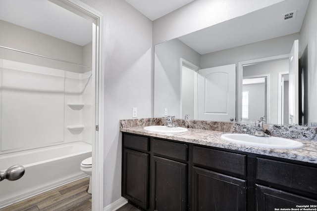 full bathroom featuring hardwood / wood-style flooring, toilet, shower / bathtub combination, and dual bowl vanity