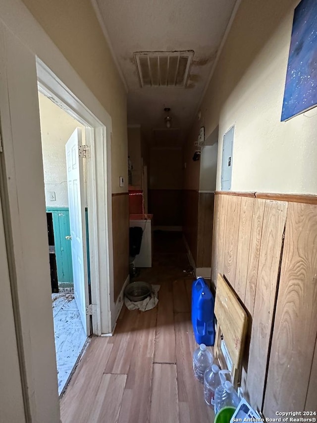 hall with wood finished floors, electric panel, and a wainscoted wall