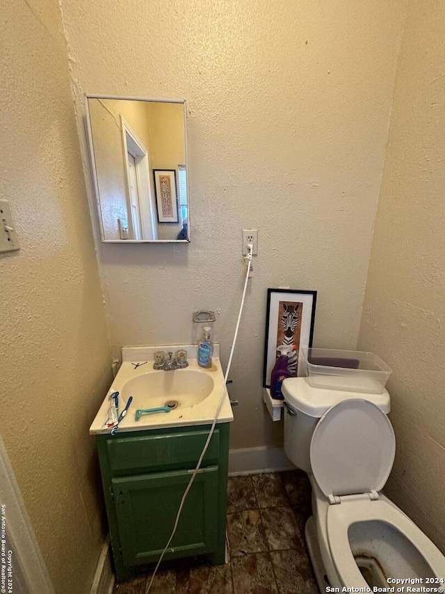half bath with toilet, vanity, and stone finish flooring