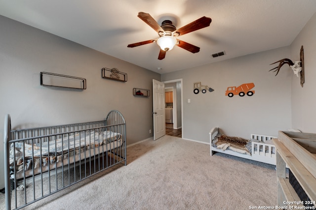 bedroom with washer / clothes dryer, carpet, a nursery area, and ceiling fan