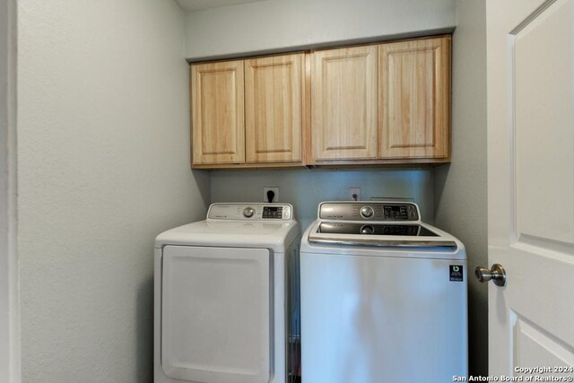 laundry room with separate washer and dryer and cabinets