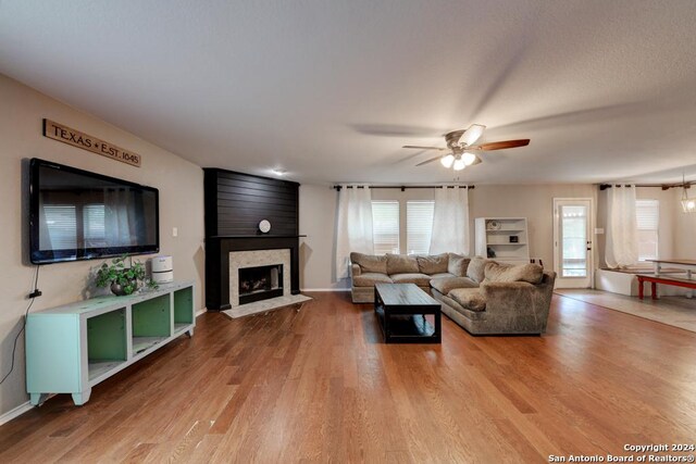 living room featuring a wealth of natural light, a fireplace, ceiling fan, and hardwood / wood-style floors