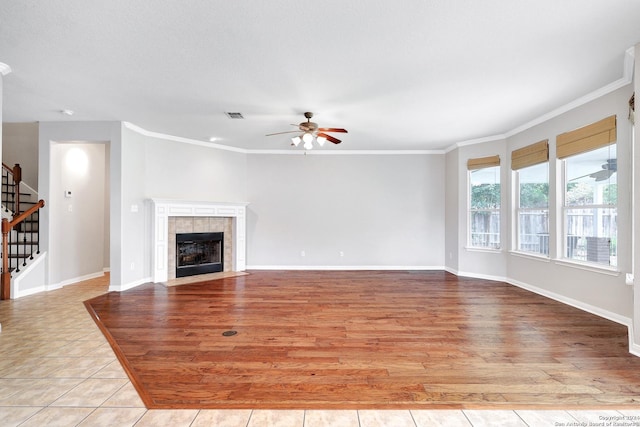 unfurnished living room featuring ceiling fan, ornamental molding, a fireplace, and light wood-type flooring