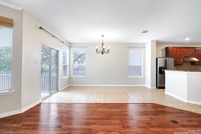 unfurnished dining area featuring a chandelier and light hardwood / wood-style floors