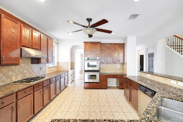 kitchen with light tile patterned flooring, backsplash, dark stone counters, ceiling fan, and stainless steel appliances