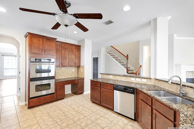 kitchen with sink, light tile patterned floors, stainless steel appliances, light stone counters, and tasteful backsplash