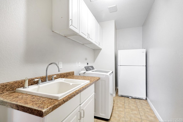 clothes washing area featuring sink, light tile patterned floors, washer / clothes dryer, and cabinets