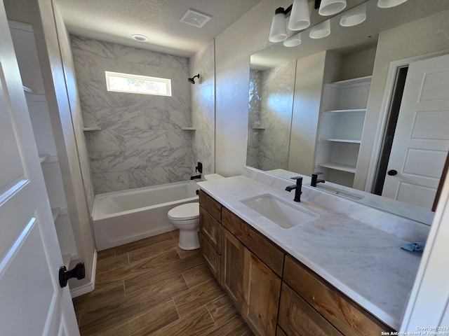 full bathroom with vanity, toilet, tiled shower / bath combo, and a textured ceiling