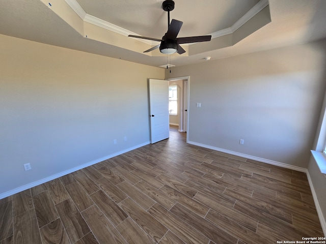 spare room with crown molding, a tray ceiling, dark hardwood / wood-style flooring, and ceiling fan