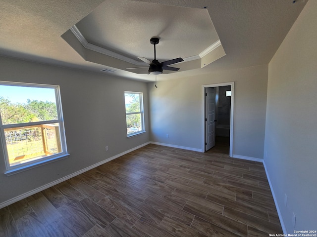 unfurnished bedroom featuring a raised ceiling, a textured ceiling, dark hardwood / wood-style flooring, ceiling fan, and crown molding