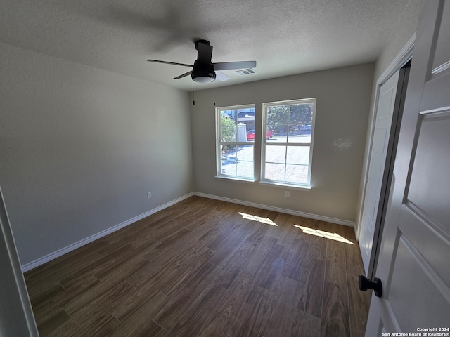 unfurnished room with ceiling fan, a textured ceiling, and dark hardwood / wood-style flooring