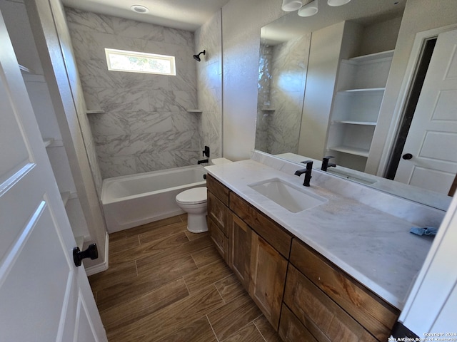 full bathroom featuring vanity, tiled shower / bath, and toilet