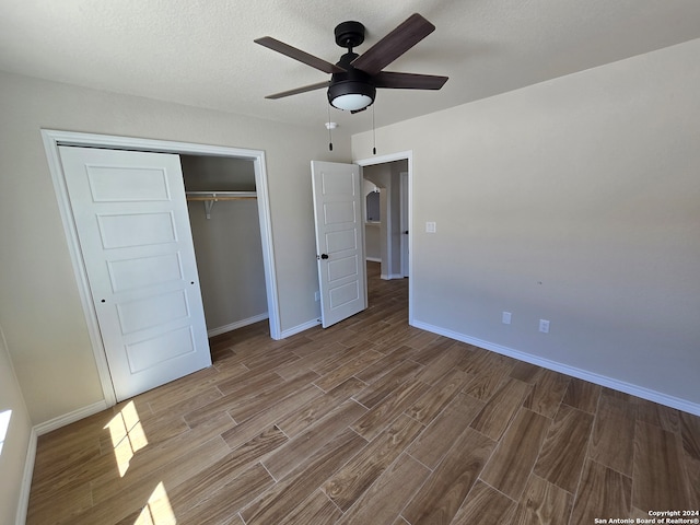 unfurnished bedroom featuring a closet, ceiling fan, a textured ceiling, and hardwood / wood-style floors