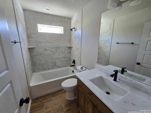 full bathroom with hardwood / wood-style flooring, toilet, tiled shower / bath, vanity, and a textured ceiling