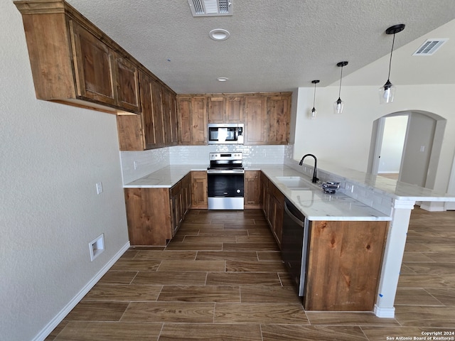 kitchen with appliances with stainless steel finishes, sink, dark hardwood / wood-style flooring, kitchen peninsula, and hanging light fixtures