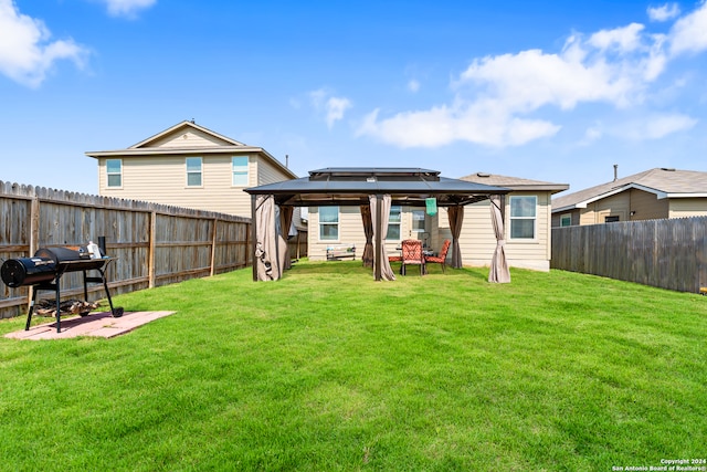 rear view of house featuring a gazebo and a lawn