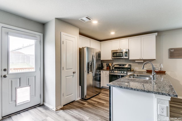 kitchen with stainless steel appliances, white cabinetry, sink, and kitchen peninsula