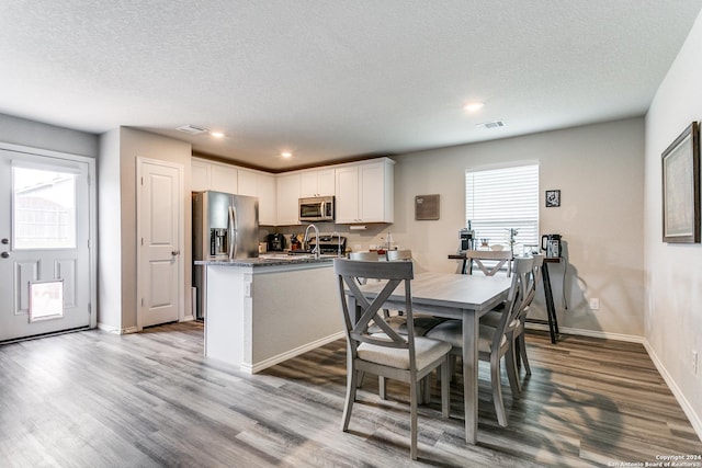 dining space with plenty of natural light, a textured ceiling, and light hardwood / wood-style flooring