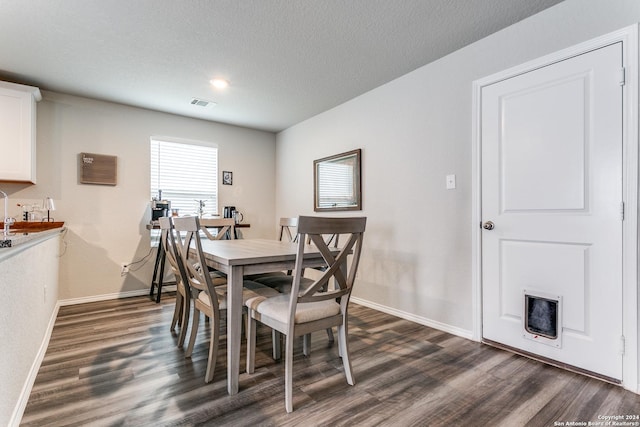 dining room with dark hardwood / wood-style floors and a textured ceiling