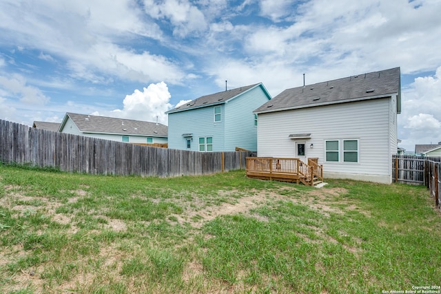 back of property featuring a deck and a lawn