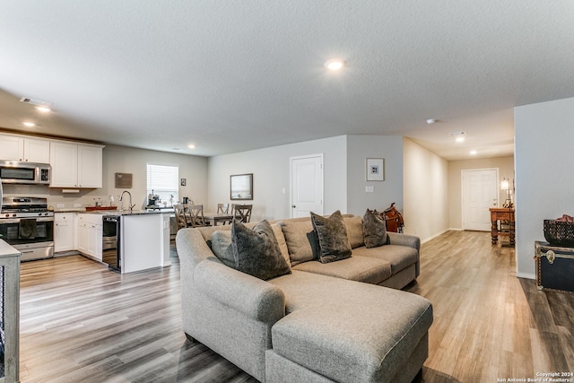 living room featuring sink, a textured ceiling, and light wood-type flooring