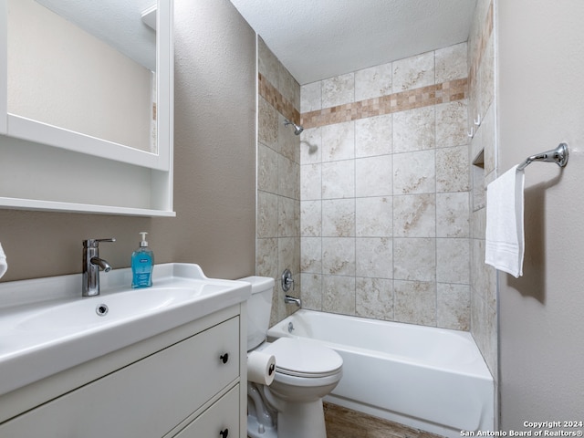 full bathroom featuring tiled shower / bath, toilet, vanity, and a textured ceiling