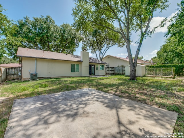 rear view of property featuring central air condition unit, a patio, and a lawn