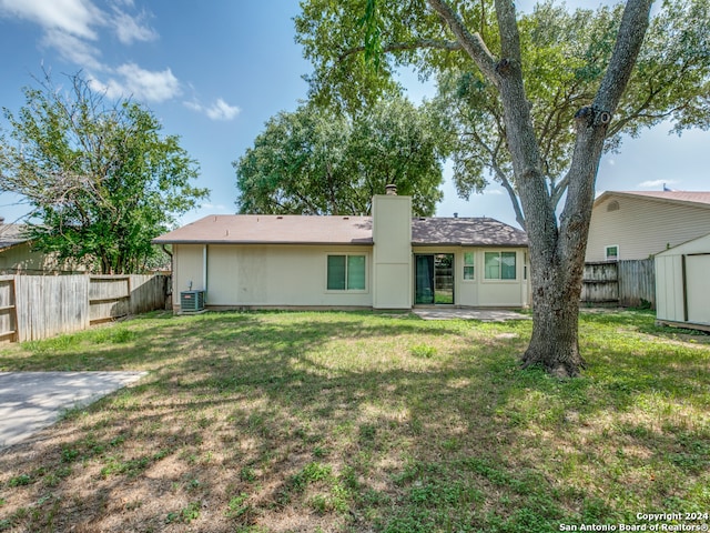 rear view of house with a storage unit, a lawn, and central AC unit