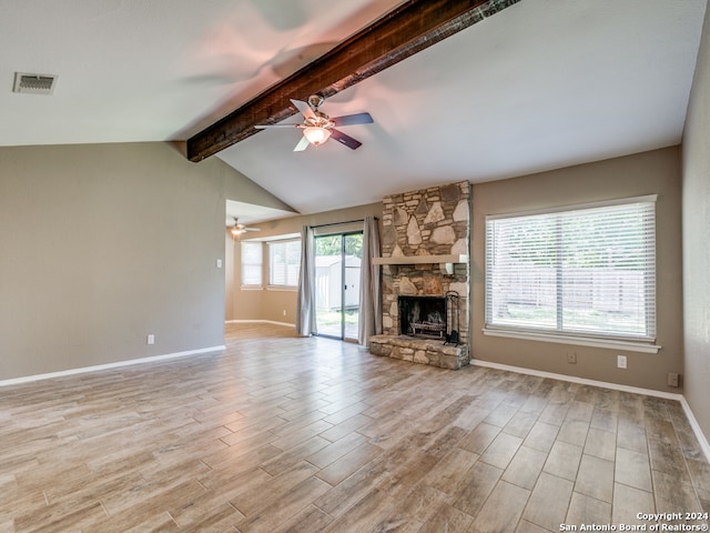 unfurnished living room with plenty of natural light, a stone fireplace, ceiling fan, and light hardwood / wood-style floors