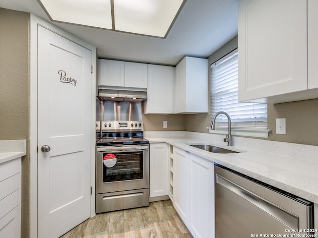 kitchen with appliances with stainless steel finishes, light hardwood / wood-style flooring, sink, light stone counters, and white cabinetry