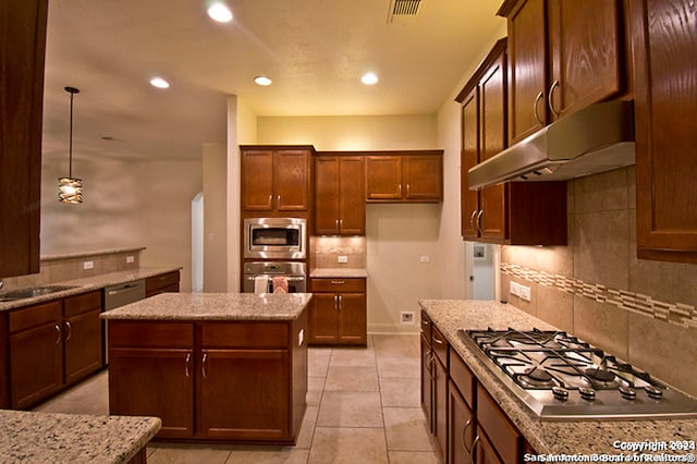 kitchen with light tile patterned flooring, tasteful backsplash, a center island, stainless steel appliances, and hanging light fixtures