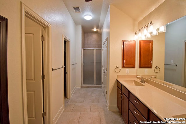 bathroom with tile patterned flooring, walk in shower, and vanity