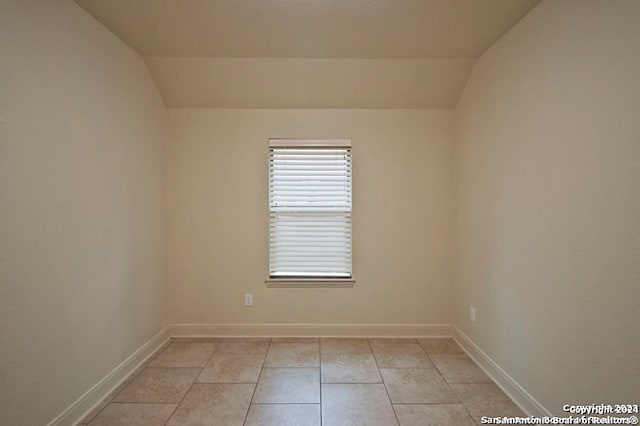 unfurnished room with vaulted ceiling and light tile patterned floors