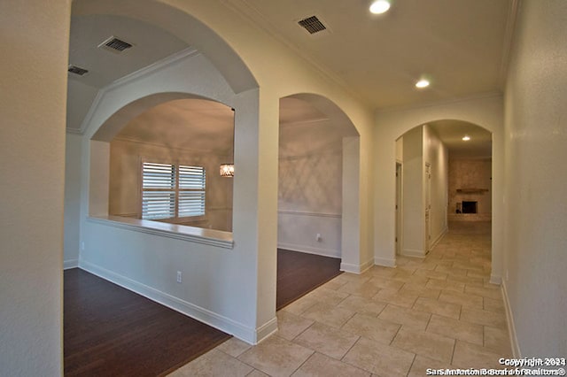 hall with ornamental molding and light hardwood / wood-style floors