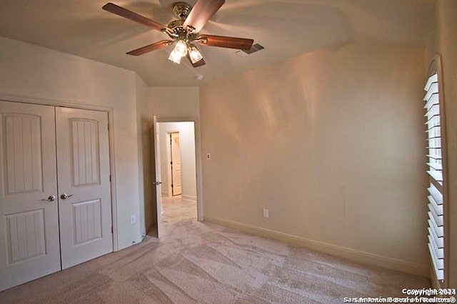 unfurnished bedroom featuring a closet, ceiling fan, and light colored carpet