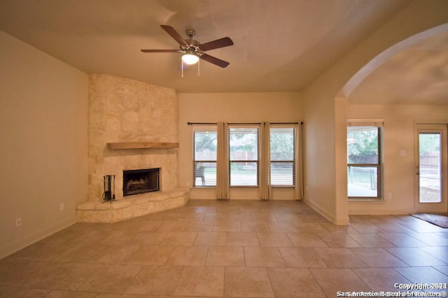 unfurnished living room featuring a fireplace, ceiling fan, a healthy amount of sunlight, and light tile patterned floors