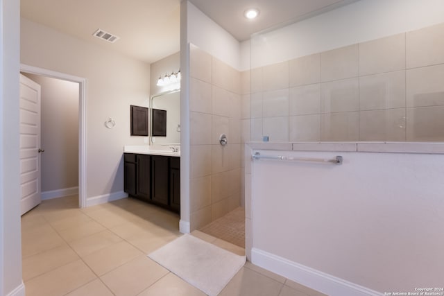 bathroom with tile patterned floors, vanity, and a tile shower