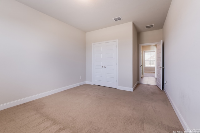 unfurnished bedroom featuring a closet and light colored carpet