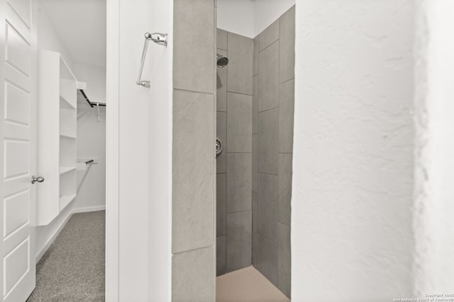 bathroom featuring a spacious closet and a tile shower