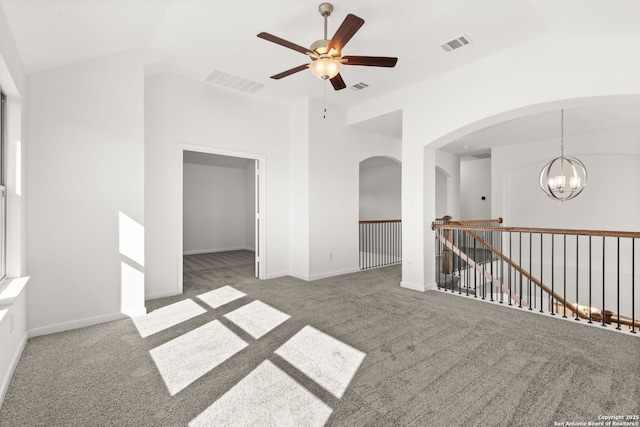 unfurnished room with ceiling fan with notable chandelier, vaulted ceiling, and carpet