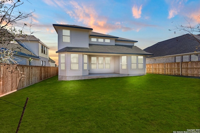 back house at dusk with a patio and a yard