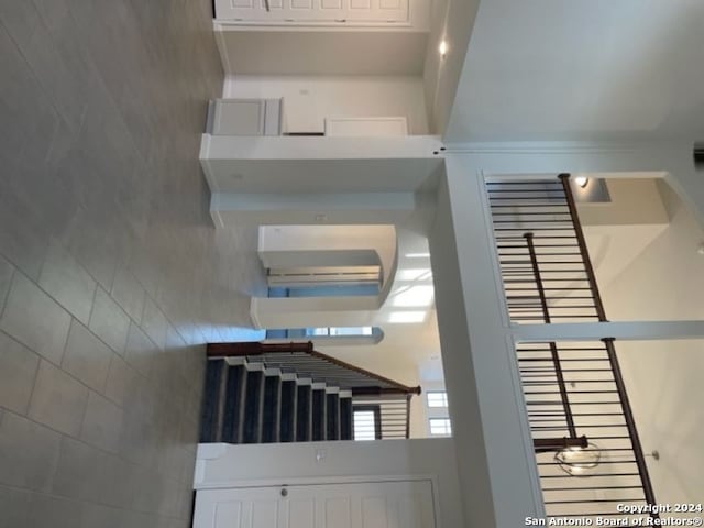 staircase featuring a towering ceiling and tile walls