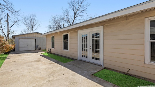 view of property exterior with french doors, a garage, and an outbuilding