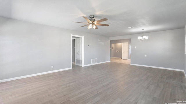 spare room with wood-type flooring and ceiling fan with notable chandelier