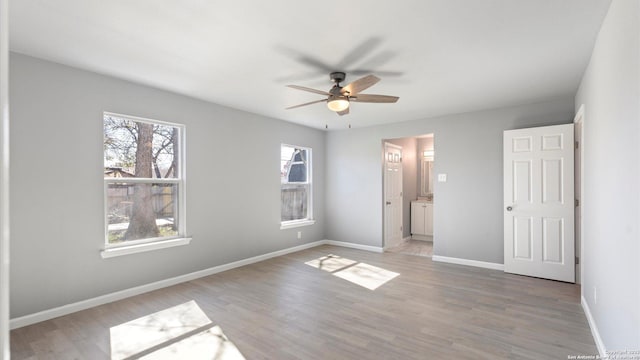 unfurnished bedroom featuring ceiling fan, ensuite bathroom, and light hardwood / wood-style floors