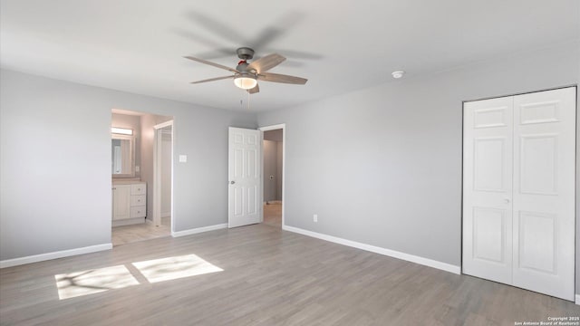 unfurnished bedroom featuring ceiling fan, ensuite bath, a closet, and light wood-type flooring